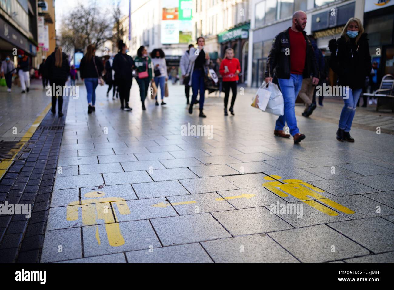 Shoppers walk through the centre of Cardiff, Wales, as new Covid-19 rules come into force. Groups of no more than six people will be allowed to meet in pubs, cinemas and restaurants in Wales, with two-metre social distancing being required in public premises and offices. Picture date: Sunday December 26, 2021. Stock Photo