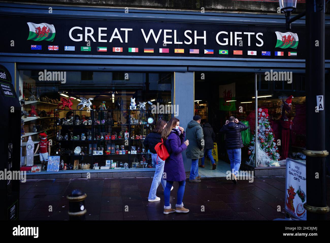 People adjust face masks as they enter the Great Welsh Gifts store in Cardiff, Wales, as new Covid-19 rules come into force. Groups of no more than six people will be allowed to meet in pubs, cinemas and restaurants in Wales, with two-metre social distancing being required in public premises and offices. Picture date: Sunday December 26, 2021. Stock Photo