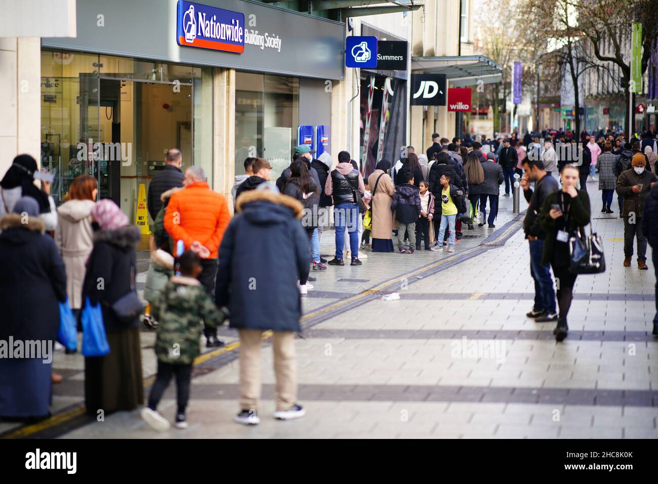 Boxing Day shoppers queue to enter shops in the centre of Cardiff, Wales, as new Covid-19 rules come into force. Groups of no more than six people will be allowed to meet in pubs, cinemas and restaurants in Wales, with two-metre social distancing being required in public premises and offices. Picture date: Sunday December 26, 2021. Stock Photo