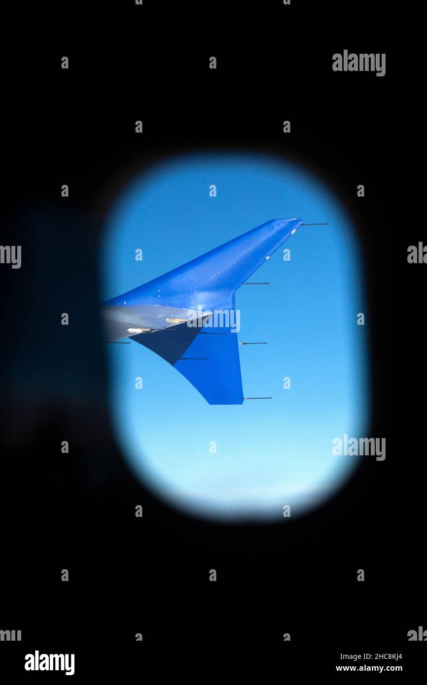 Airliner Wing Fin, viewed from a passenger seat, looking through a porthole of  plane's fuselage Stock Photo