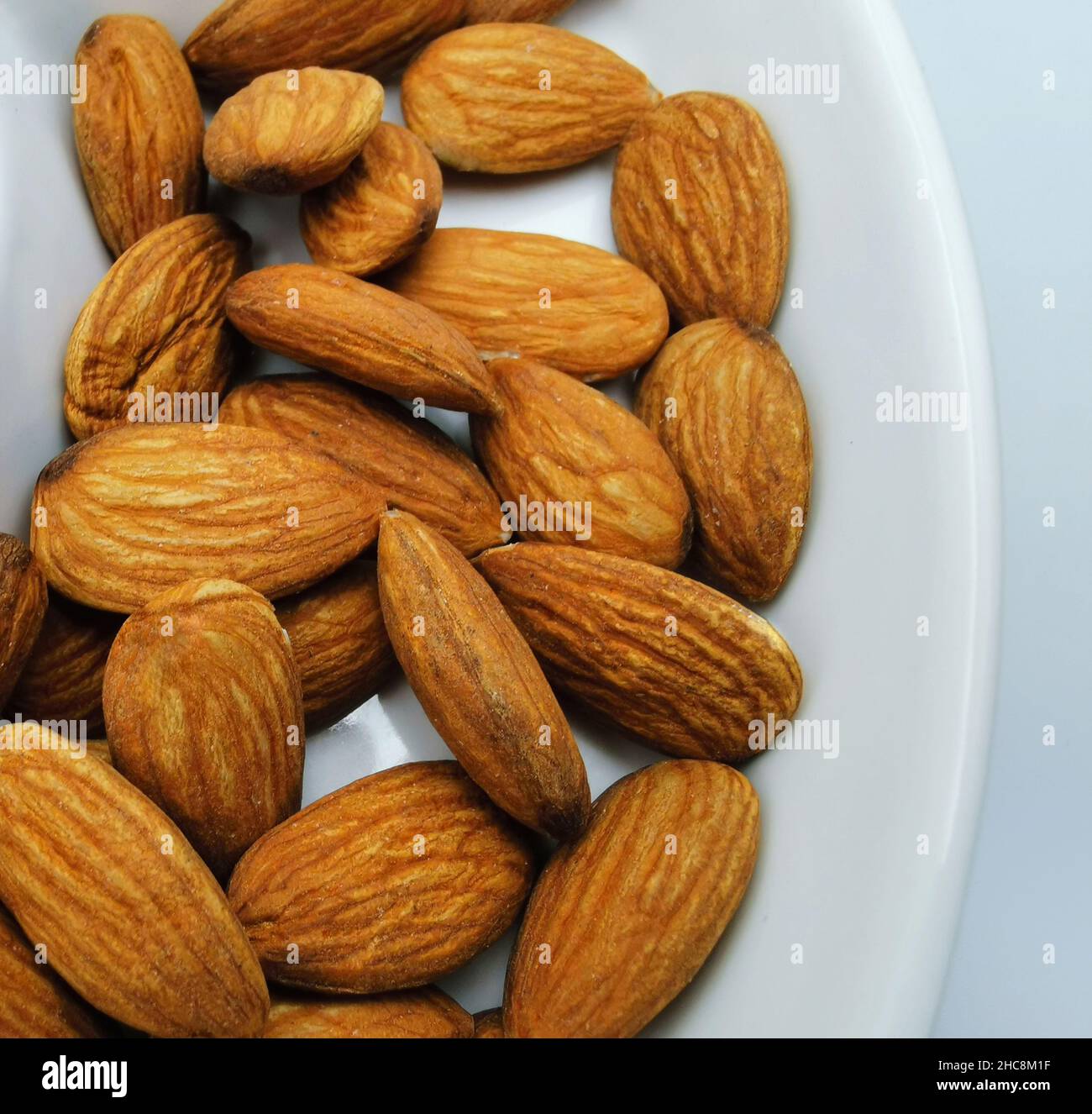 peeled almonds close up on white plate Stock Photo