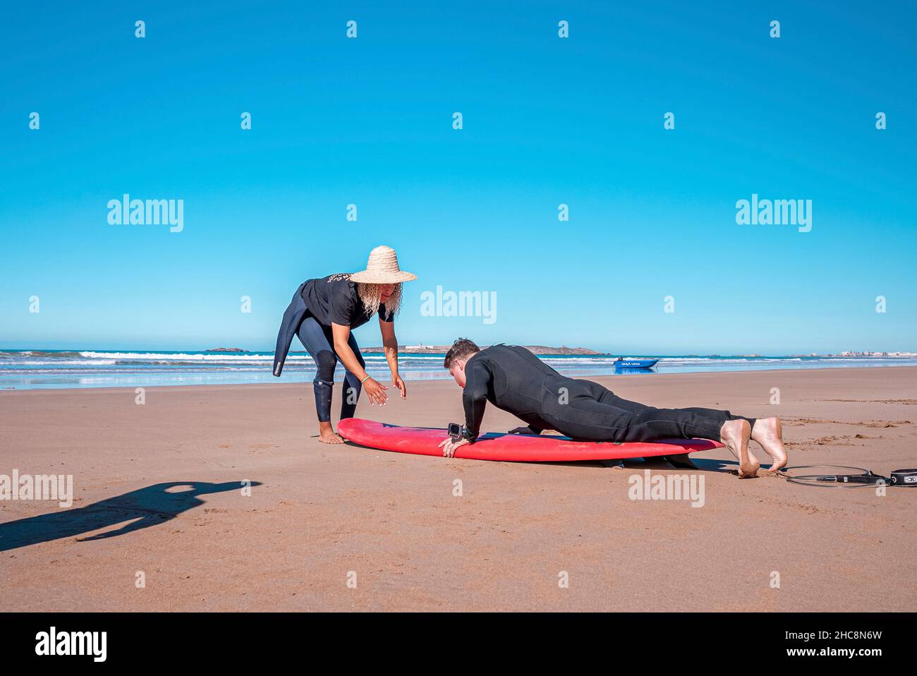 Male instructor demonstrating how to stand up on surfboard to man Stock