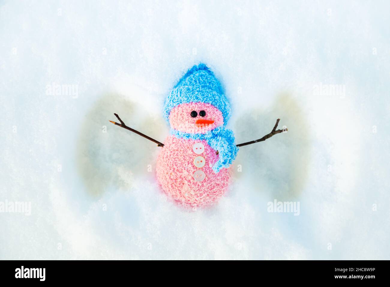 Cute snowman makes a snow angel. Winter background with copy space. Stock Photo