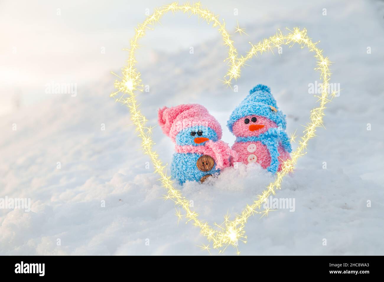 Cute homemade snowmen in a heart made of sparklers. Valentine's day card. Winter background. Stock Photo