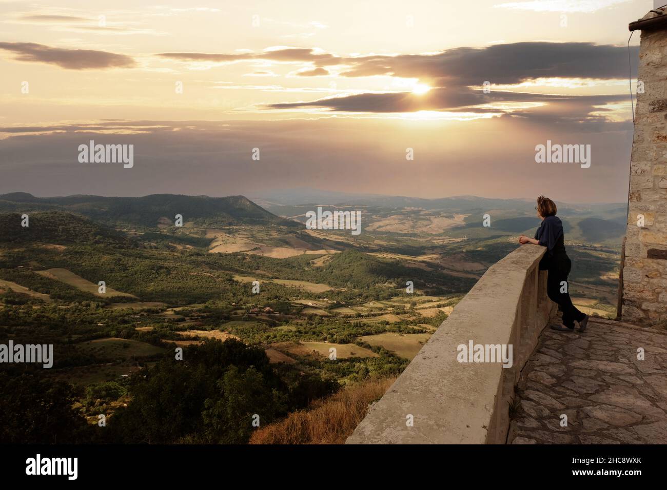 A woman looking into the distance at a scenic landscape during the early hours of the morning Stock Photo