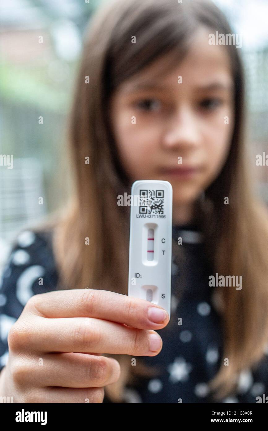 Shallow depth of field (selective focus) details with the hands of a 9 years old girl holding a COVID-19 Antigen Rapid Test, with a positiv result. Stock Photo