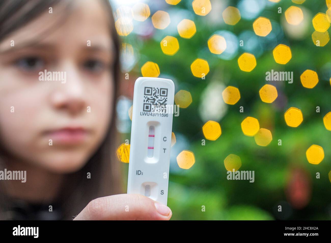 Shallow depth of field (selective focus) details with the hands of a 9 years old girl holding a COVID-19 Antigen Rapid Test, with a positiv result. Stock Photo