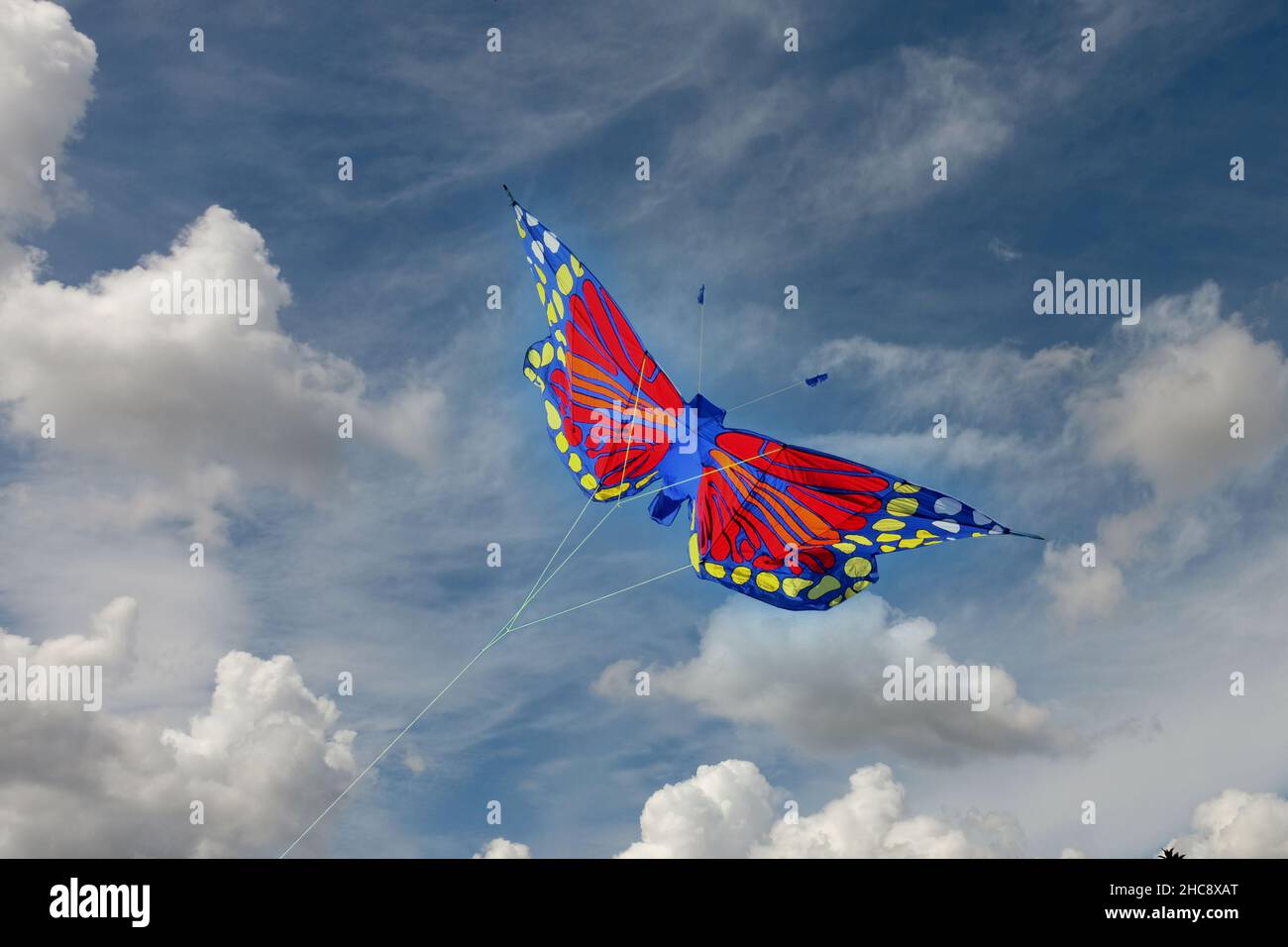 A kite in the shape of a butterfly flying against a blue sky. Stock Photo