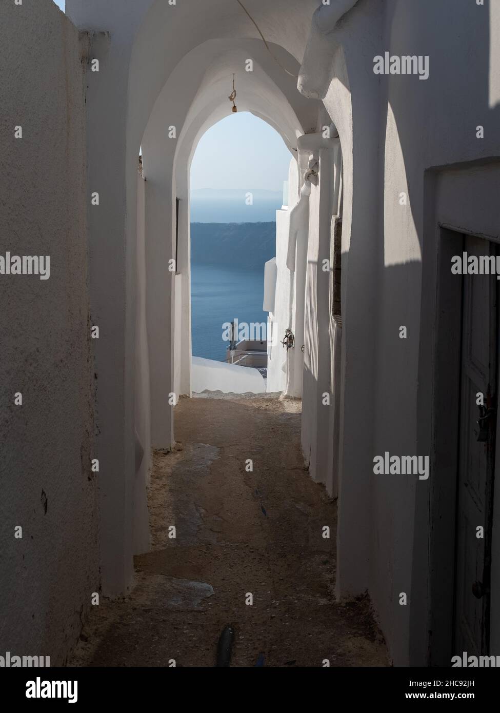 A vaulted passageway toward  the Aegean sea with no people. Taken at the end of a sunny summer day in the Aegean Island of Santorini, Greece Stock Photo