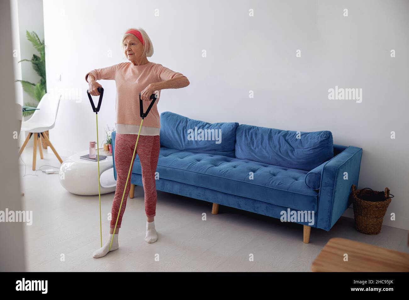 Elderly lady training with exercise band at home Stock Photo