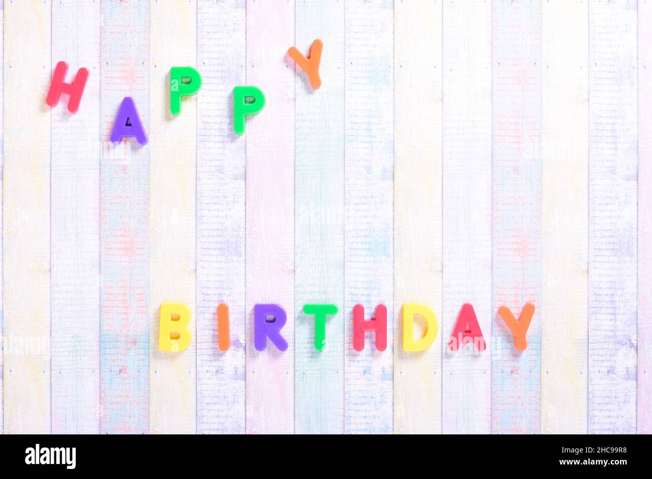 Photograph of some magnet letters with the English text of Happy Birthday on a colored cardboard background.The photograph is shot in horizontal forma Stock Photo