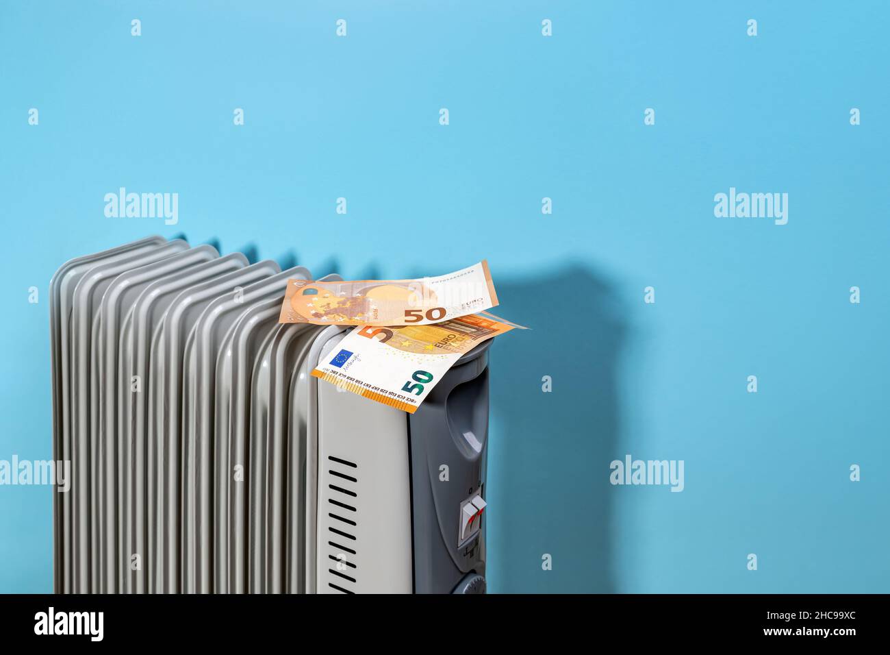 Fifty euro banknotes on a portable oil filled electric heater near blue
