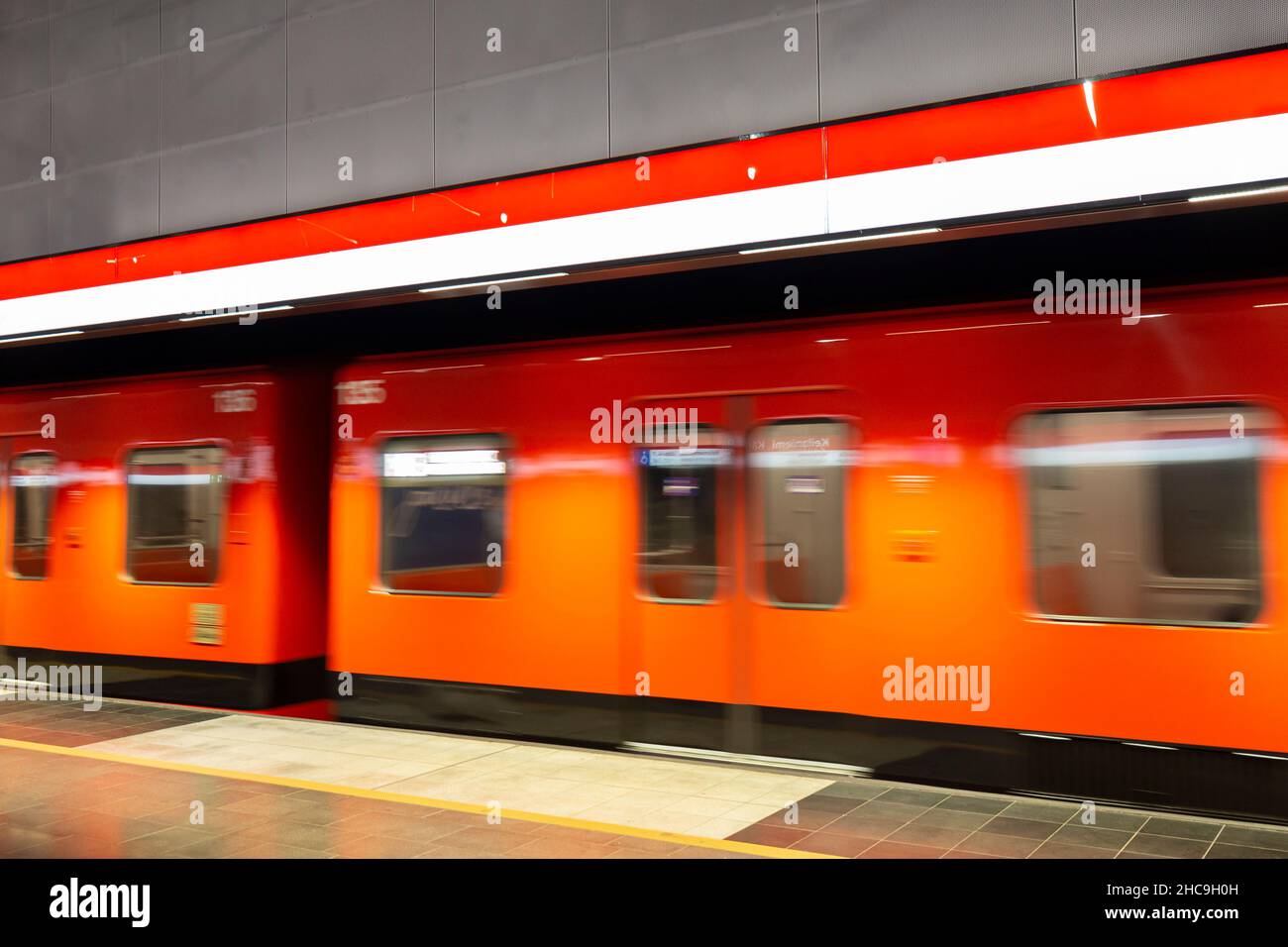 Orange subway train in motion at an underground station in Helsinki, Finland. Stock Photo