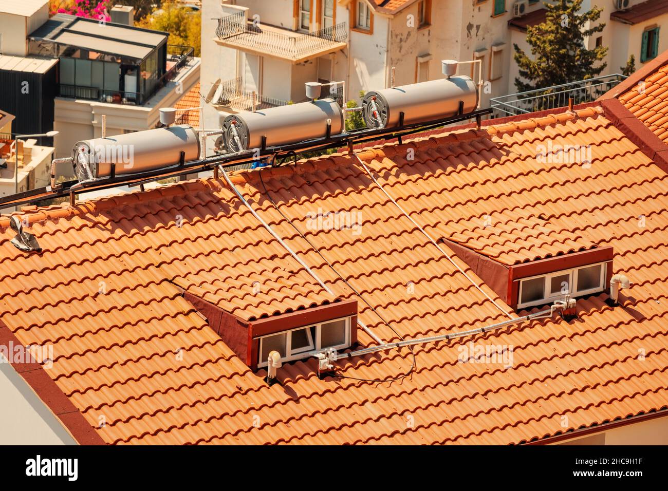Solar panels and a water barrel are installed on the roof of the house ...