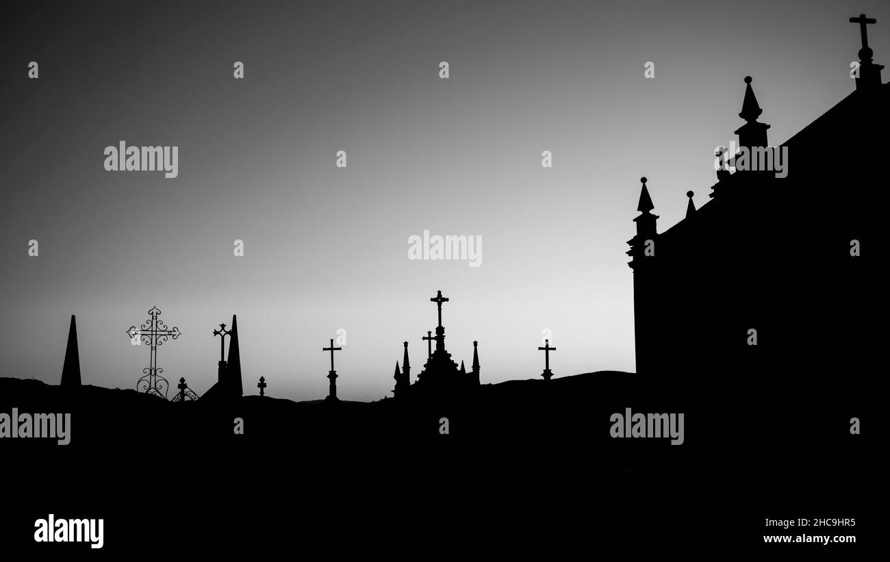 Silhouettes of crosses in the cemetery during dawn. Black and white photo. Stock Photo