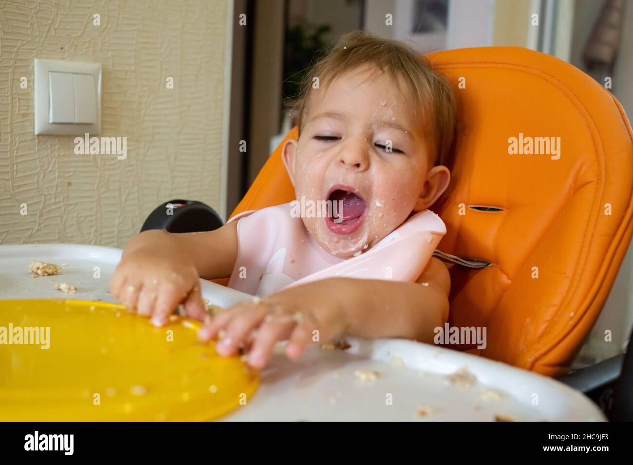 sleepy baby yawn after food in baby chair, child want to sleep Stock Photo