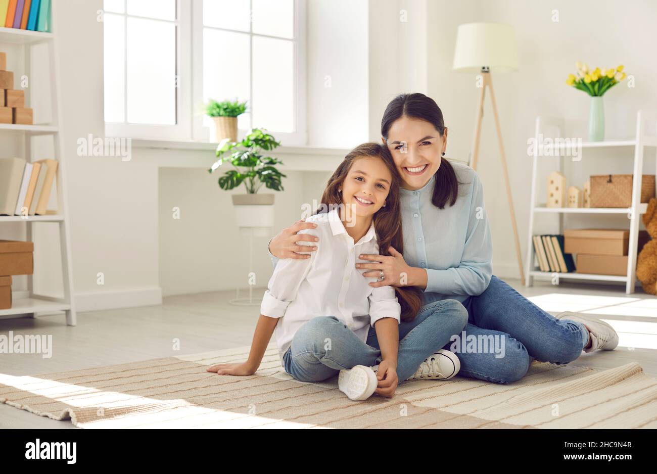 Portrait of smiling mom and daughter relax at home Stock Photo