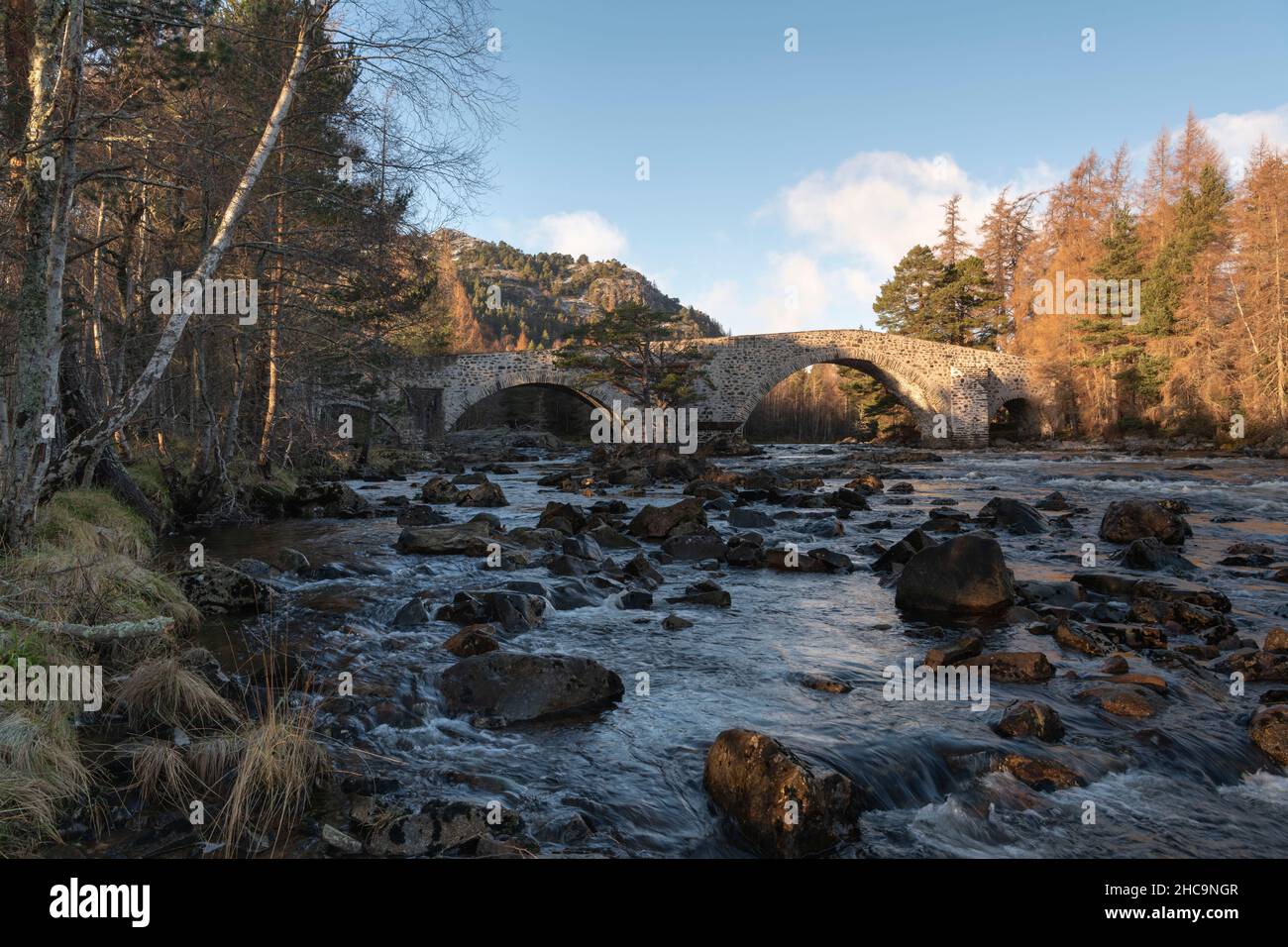 The Tree-Lined Banks of the River Dee and the Old Invercauld Bridge in the Cairngorms National Park Near Braemar on a Sunny Winter Morning Stock Photo