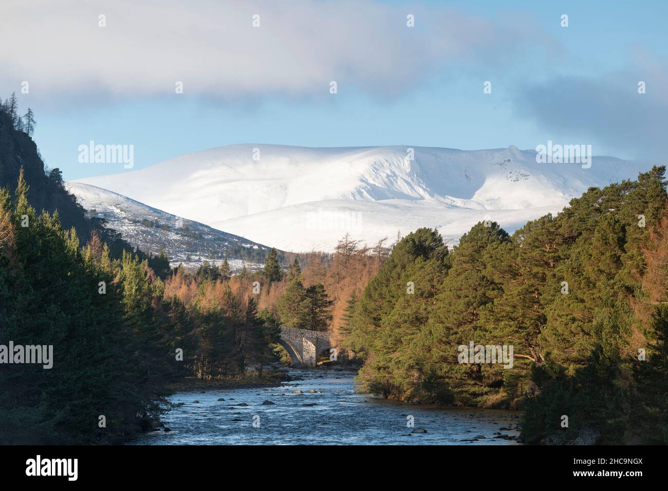 A View Along the River Dee on Balmoral Estate, Near Braemar, Towards the Old Bridge of Dee, with Snow-Covered Hills and Mountains in the Background Stock Photo