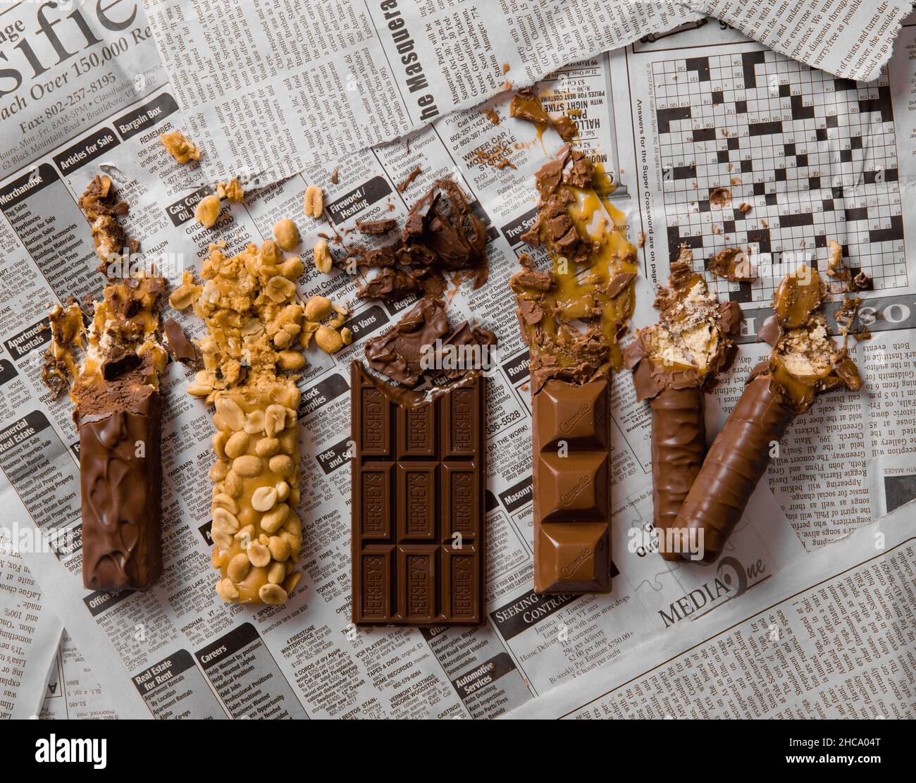 Closeup of the five popular candy bars smeared across a newspaper. Stock Photo