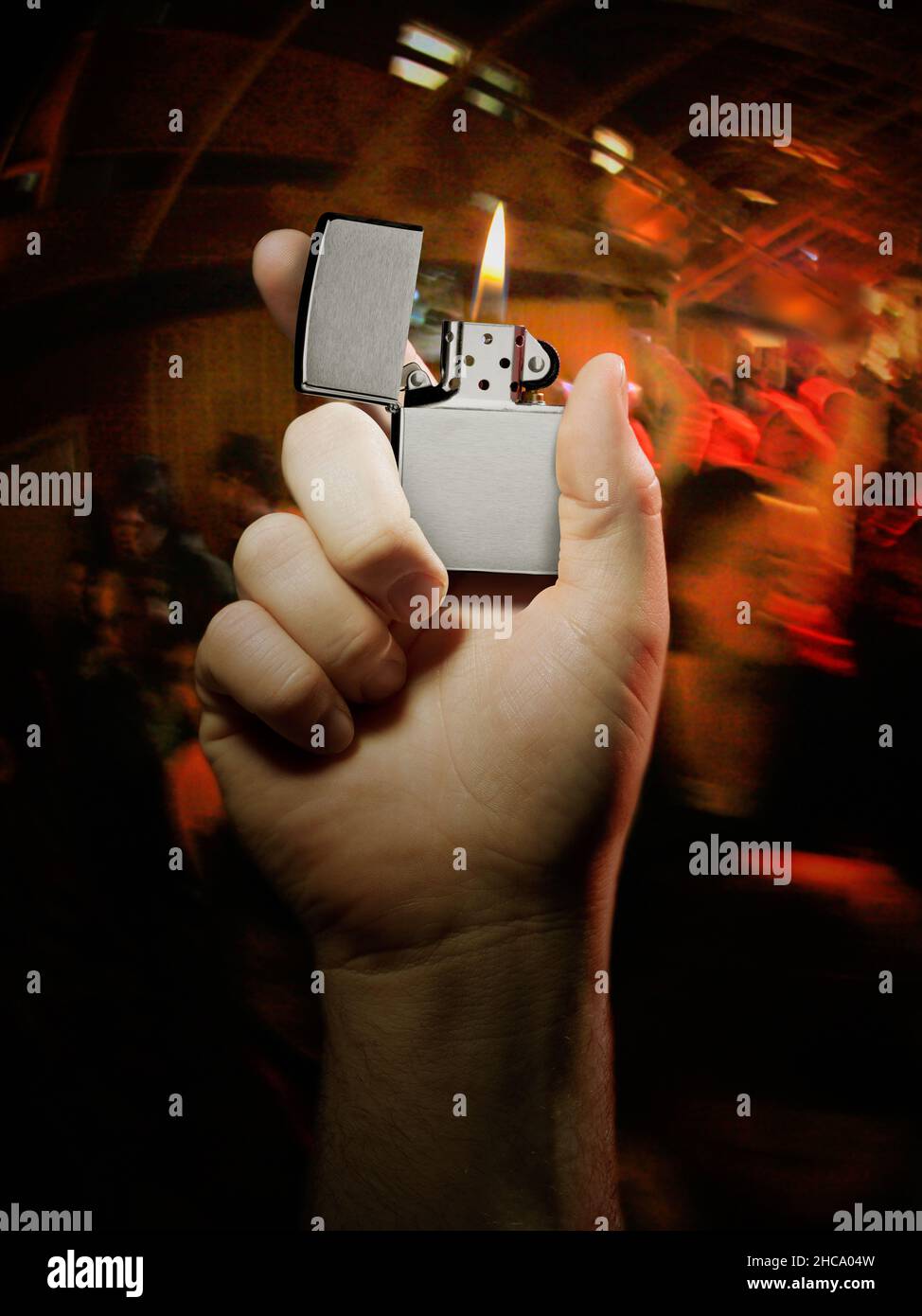 Vertical closeup of the right hand holding a lit Zippo lighter at a rock concert. Stock Photo