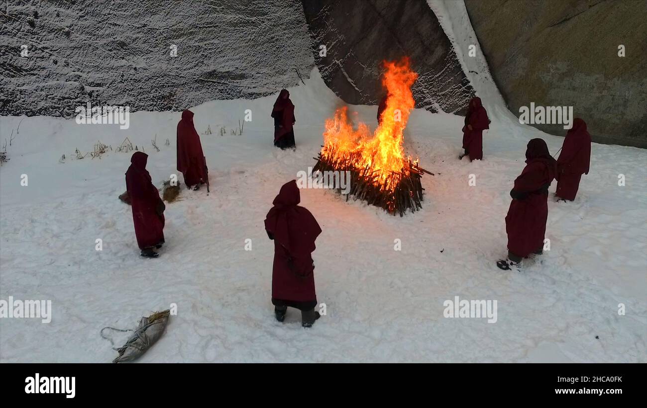 Torchlight procession. Ritual fire. Footage. Group of monks in hood robe walking along winter snow trail in forest. Group of monks in hood robe walkin Stock Photo