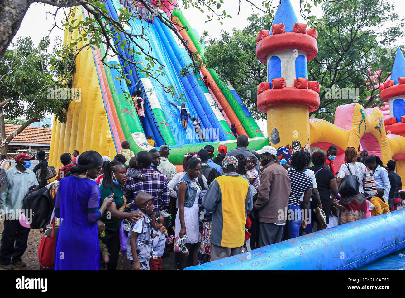Nairobi, Kenya. 25th Dec, 2021. Kenyan families wait in queue for their children to get a chance to slide on a bouncing castle at a carnival on Christmas Day. For many years, Kenyans living in Nairobi and its environs have spent Christmas Day at the Uhuru and Central parks. However, that is not the case this year, as the two parks remain closed for renovations. This did not stop them from enjoying the day in small spaces that were available. Credit: SOPA Images Limited/Alamy Live News Stock Photo