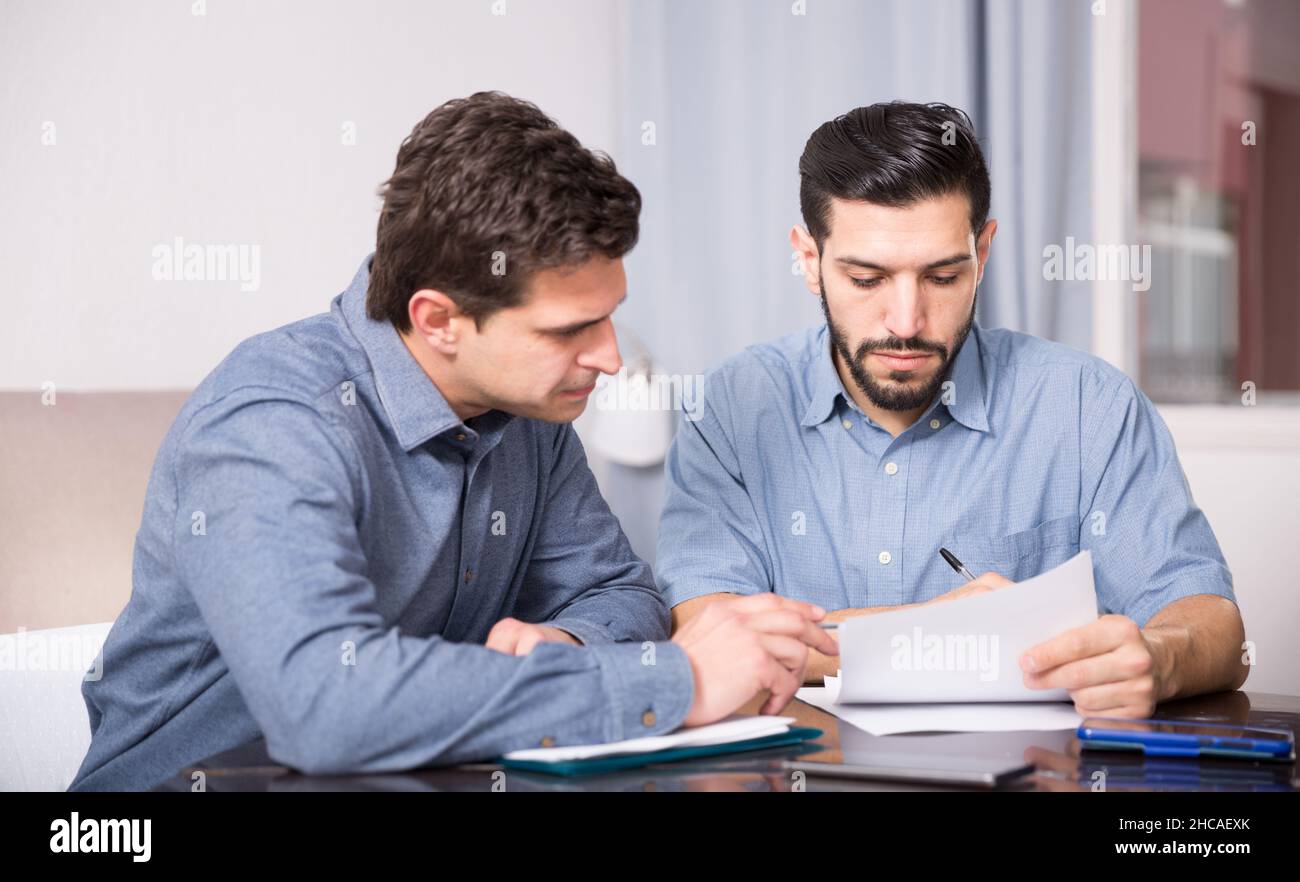 Two serious males with documents at table Stock Photo