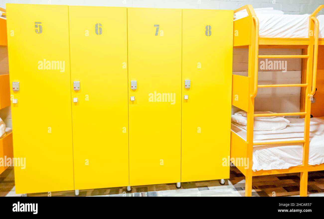 Yellow Lockers and Bunk beds with freshly made beds in a modern hostel room Stock Photo