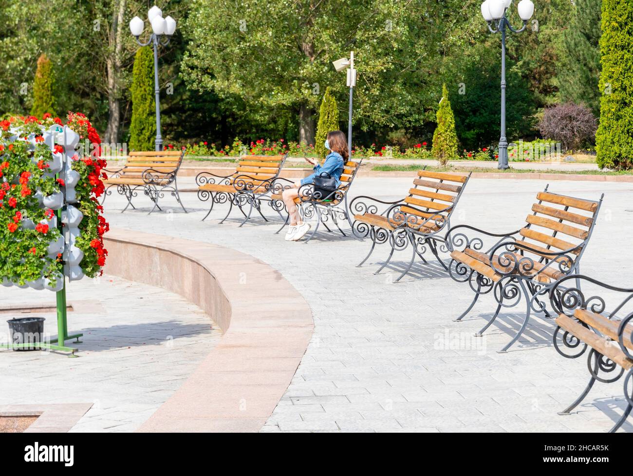 woman sitting on the bench in the First President's Park - an urban landmark in Almaty, Kazakhstan Stock Photo