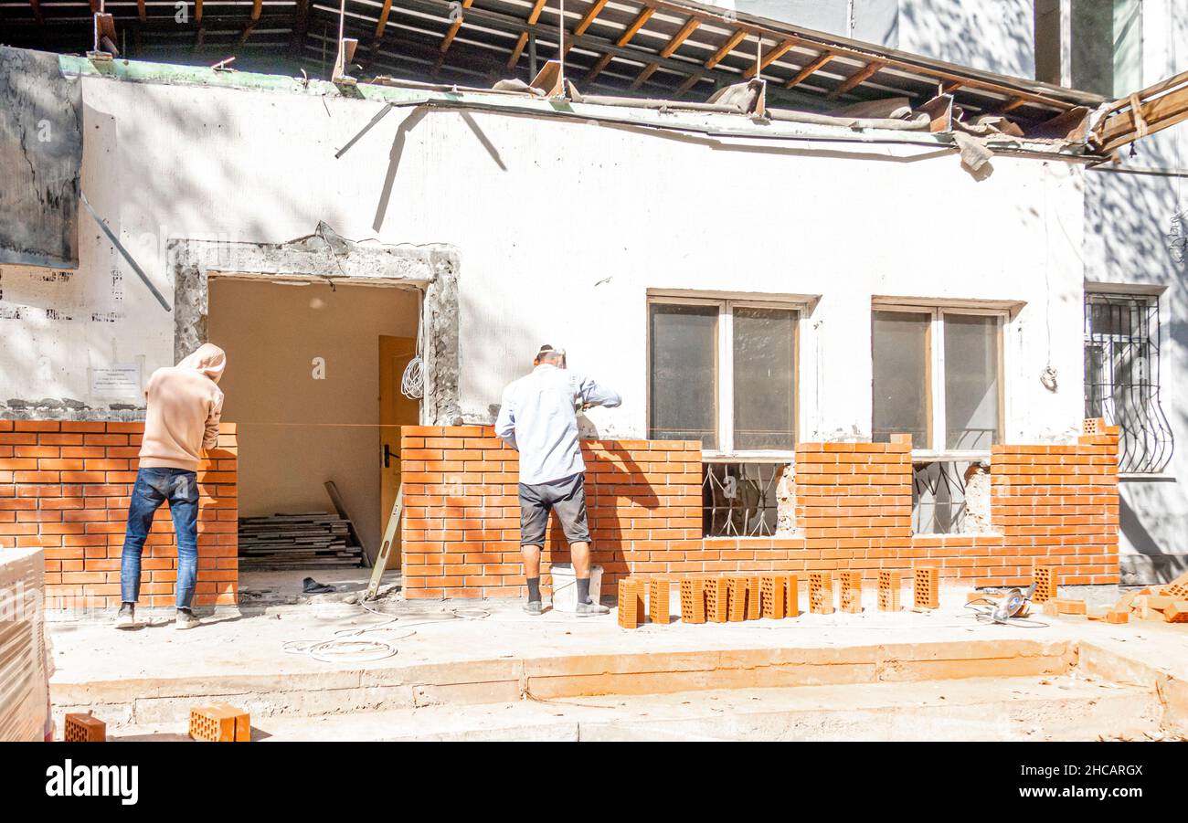 Two workers laying bricks on a new wall at a house construction site in Almaty, Kazakhstan Stock Photo