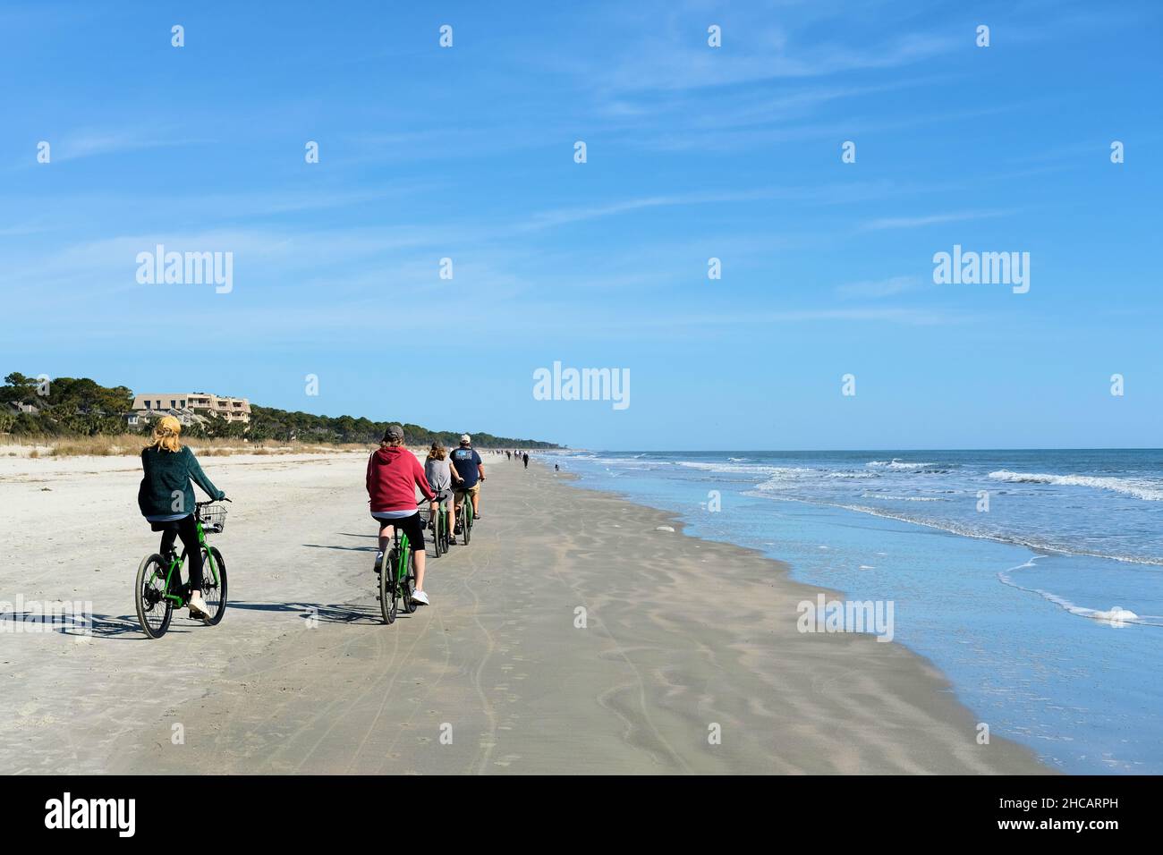 A family of four bicycling on the beach in Hilton Head, South Carolina on winter holiday in December enjoying the mild sunny weather in the lowlands. Stock Photo