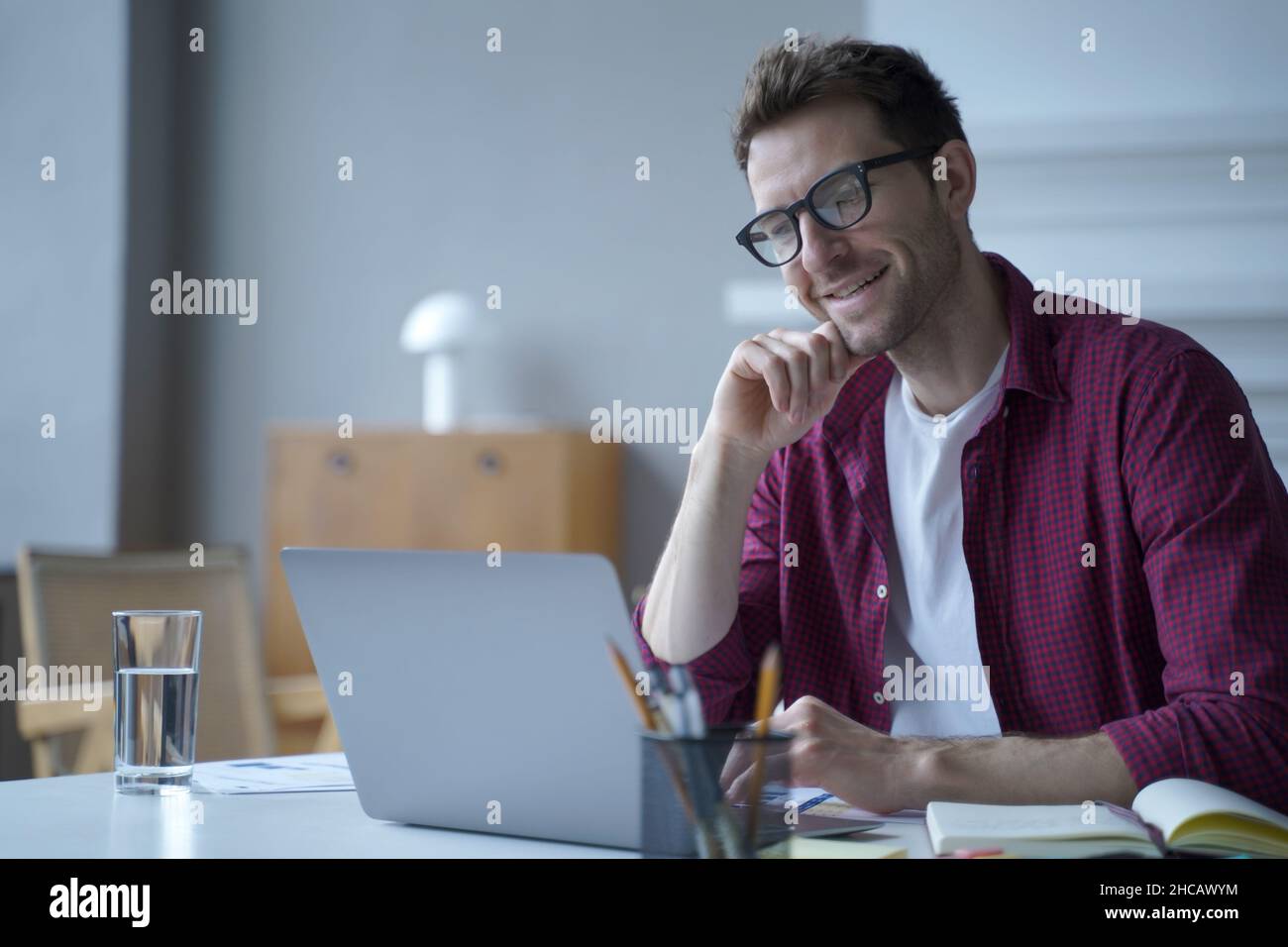 Young handsome smiling german man office worker in glasses enjoying video call on laptop computer Stock Photo
