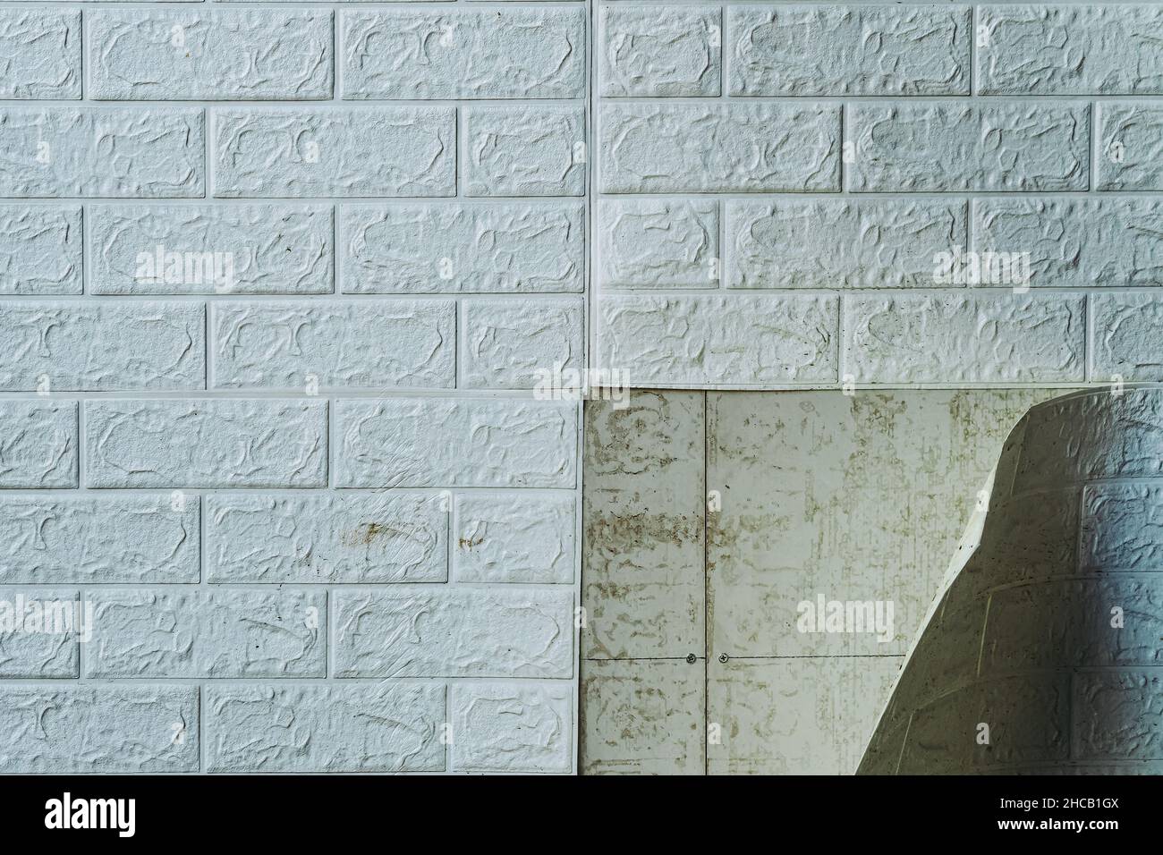 The wallpaper begins to peel off. Old white bricks wallpaper peeled off from the wall inside the