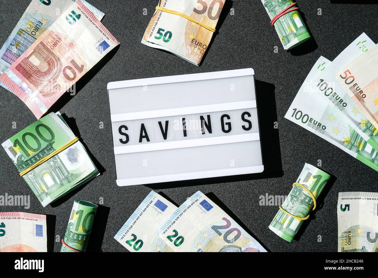 Lightbox board with word SAVINGS in black letters around Euro banknotes ...