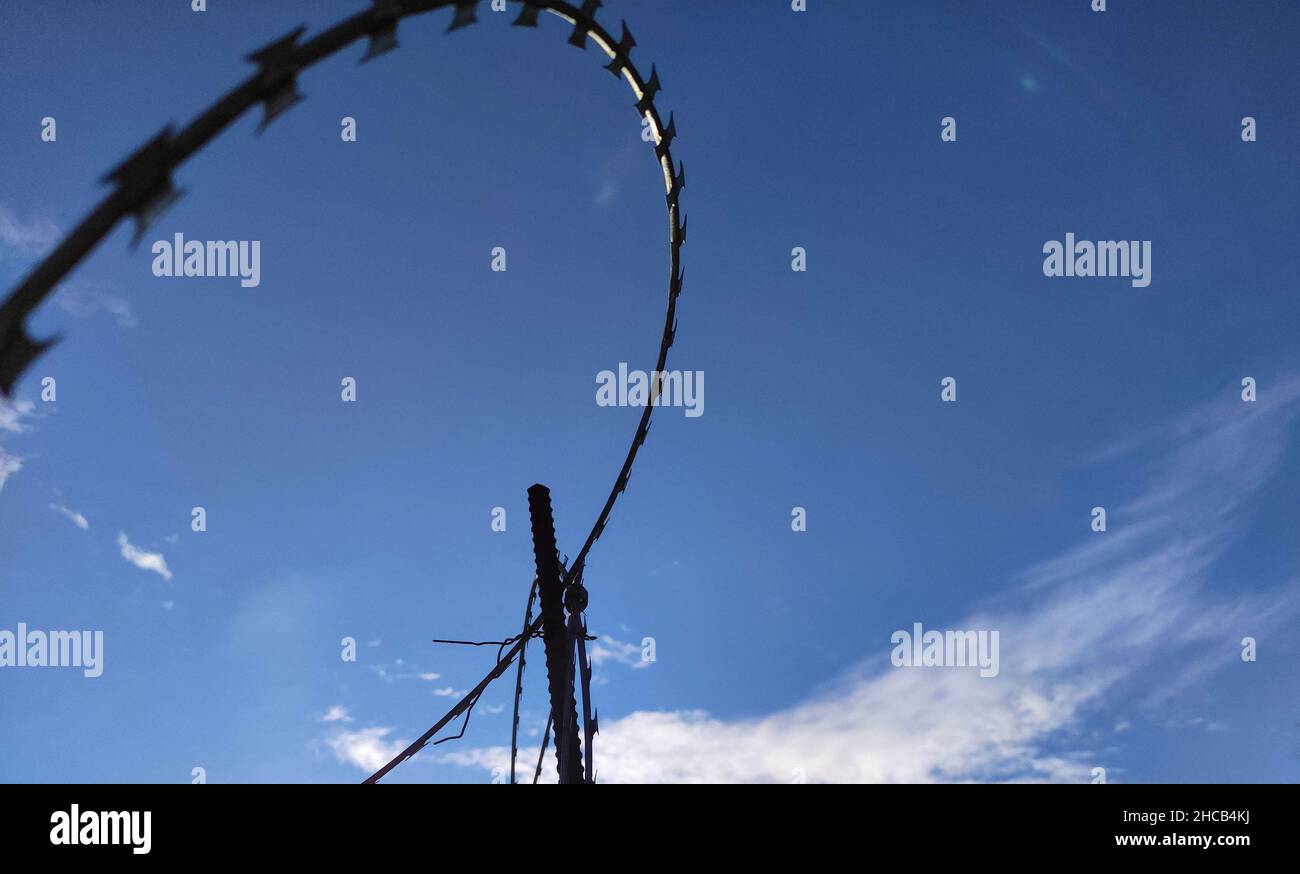 Barbed twisted wire metal fence close photo, prison and freedom border line conceptual background Stock Photo