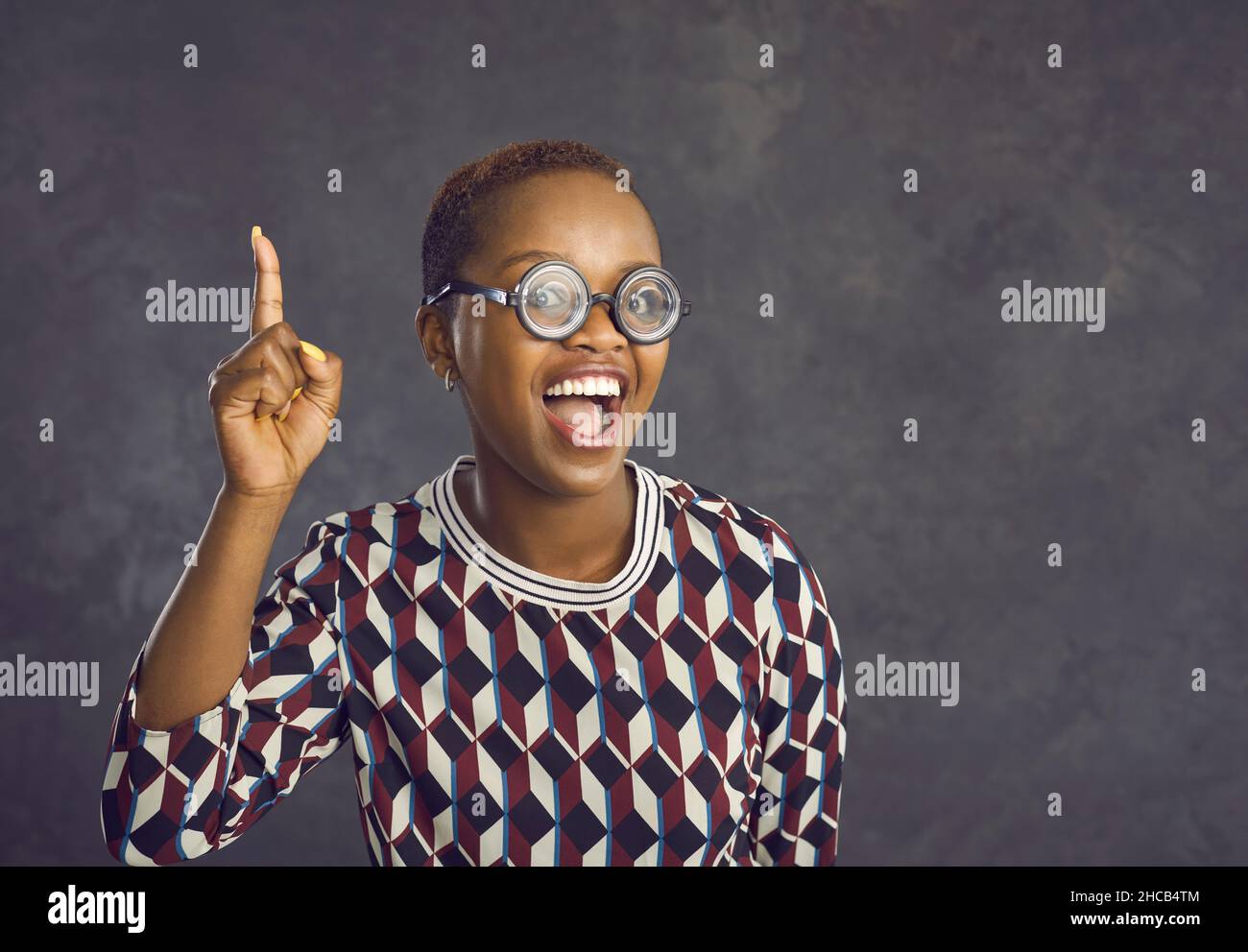 Cheerful woman in funny glasses raises her index finger to indicate that she has an idea or thought. Stock Photo