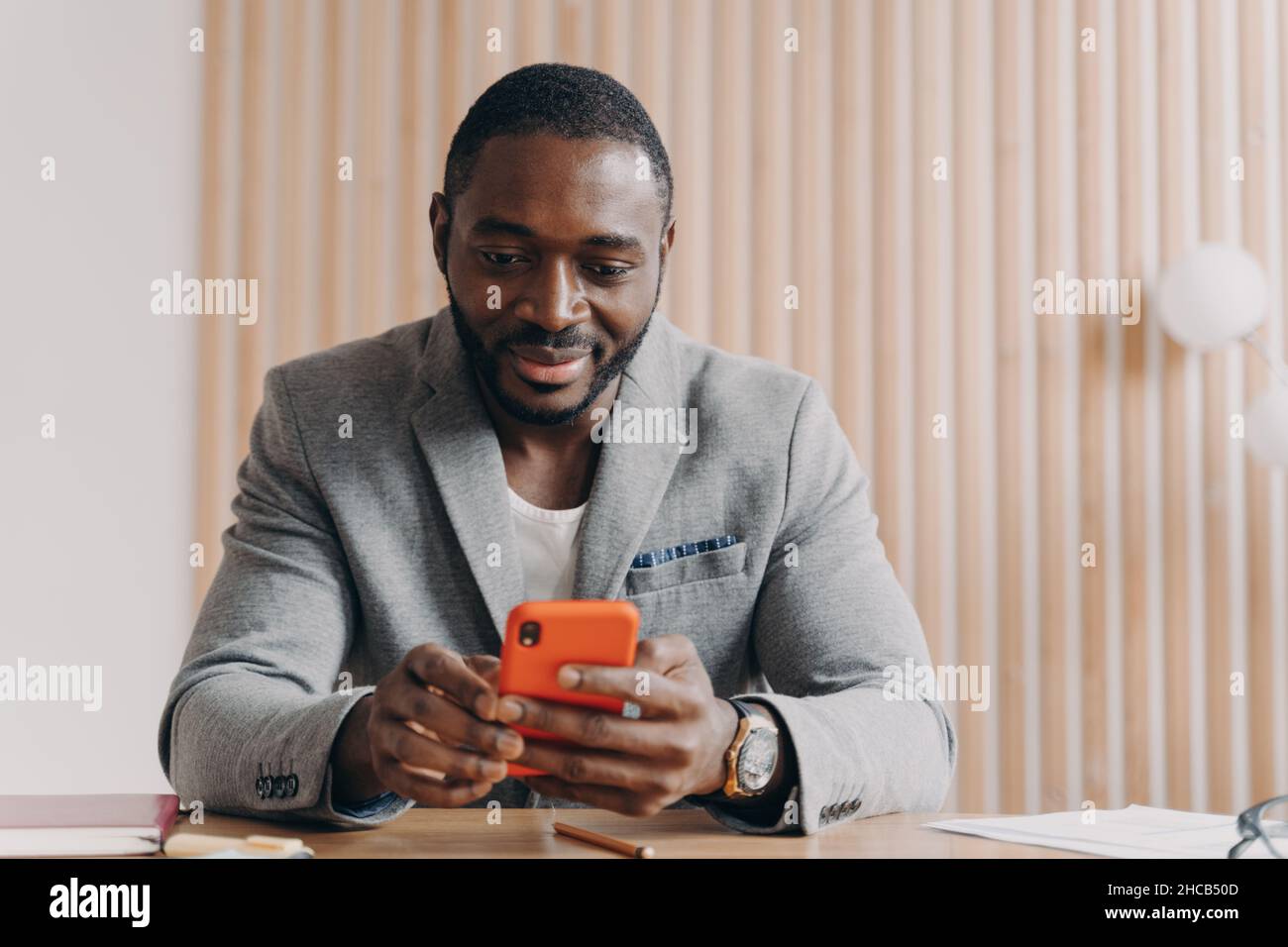Young smiling african male entrepreneur sitting at office desk and ...
