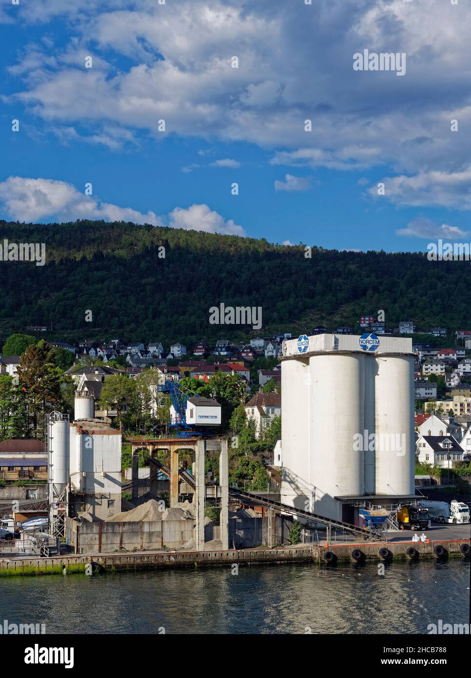 The Norcem Cement Factory and Silos set alongside Bergens waterfront with Houses and commercial property beside it amongst the trees. Stock Photo
