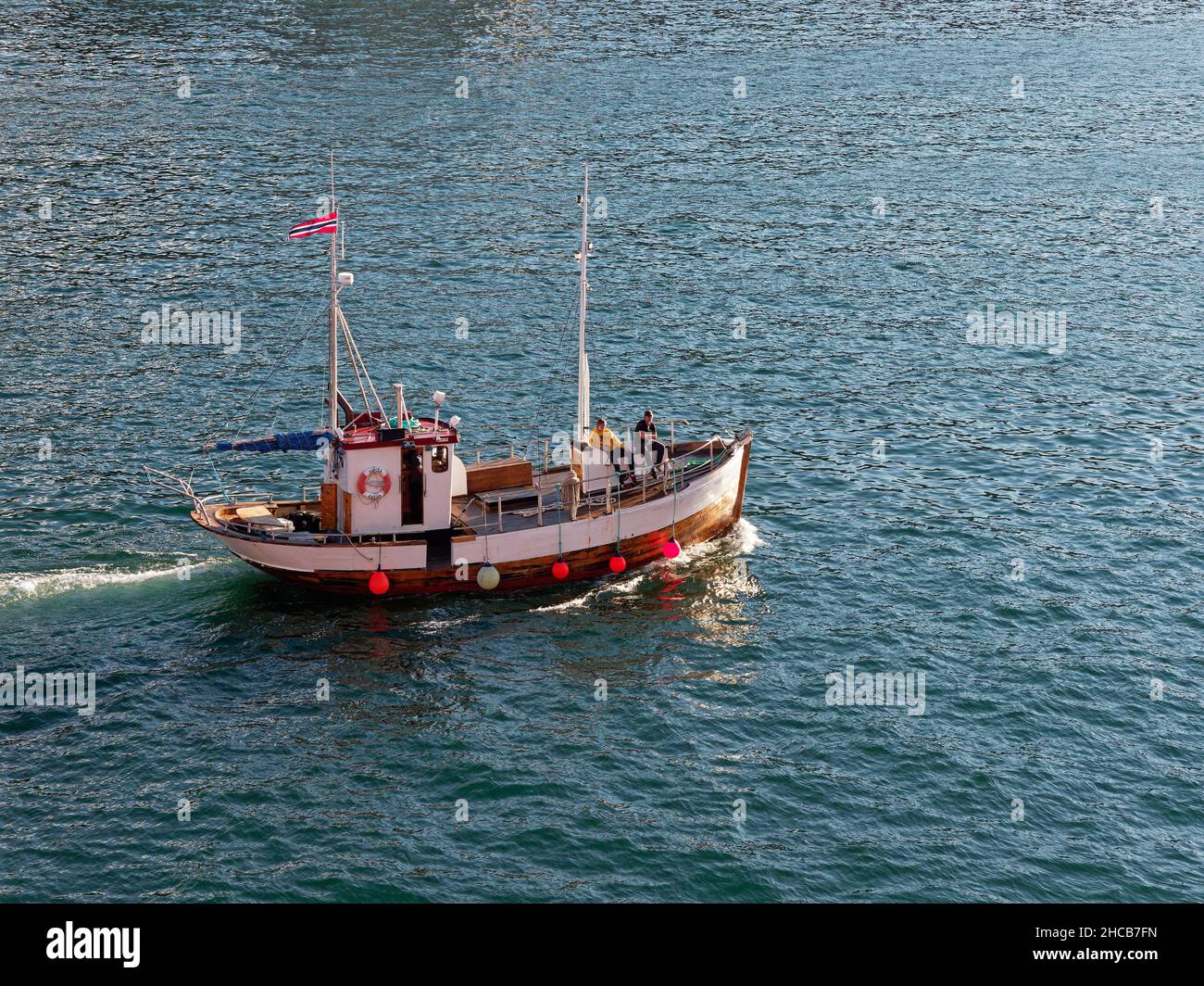 A Traditional restored wooden Fishing Vessel departs Bergen for a Pleasure Cruise on the calm waters of the Fjord on a bright Summers day. Stock Photo