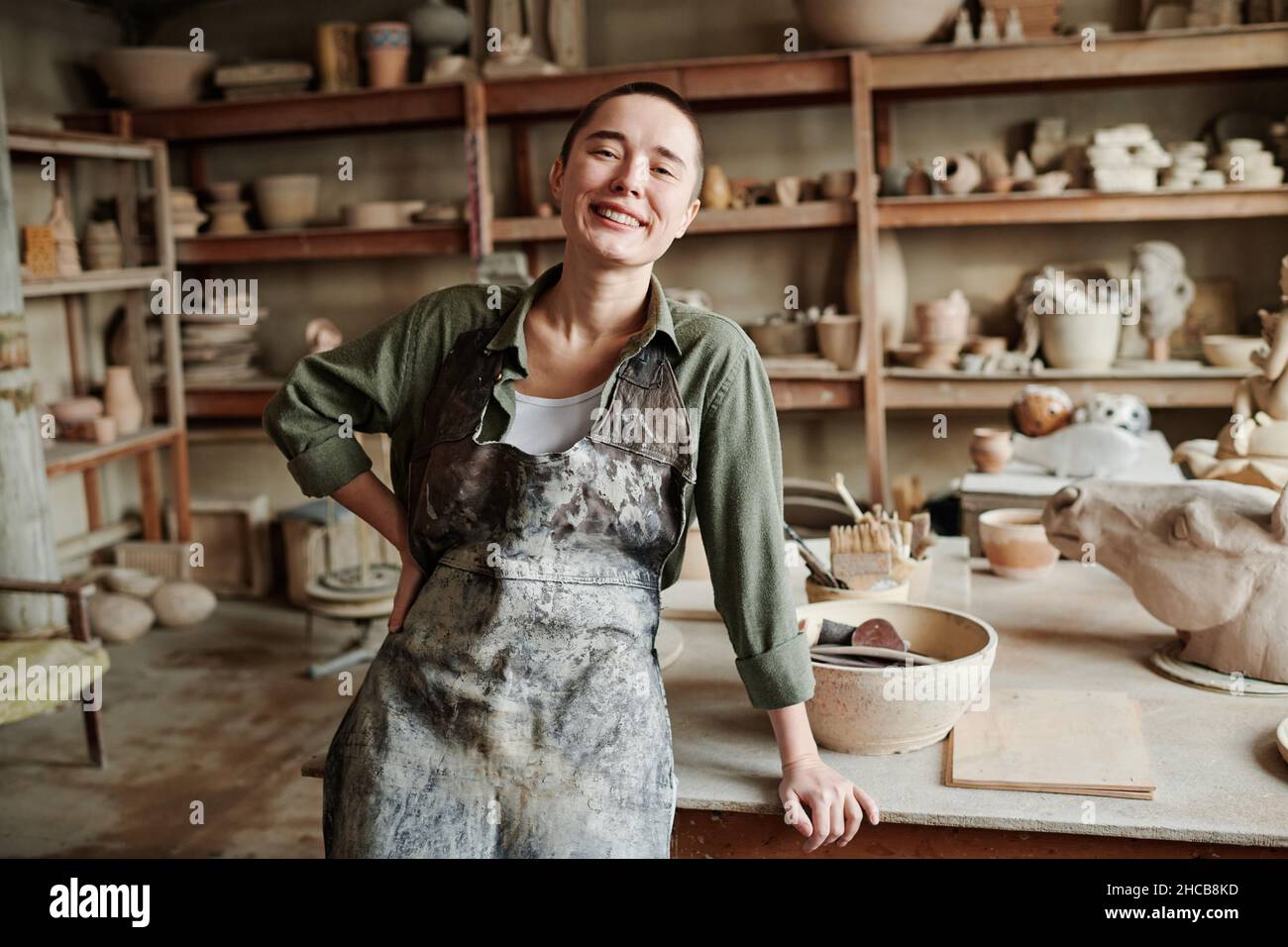 Portrait of young happy woman in apron smiling at camera while working ...