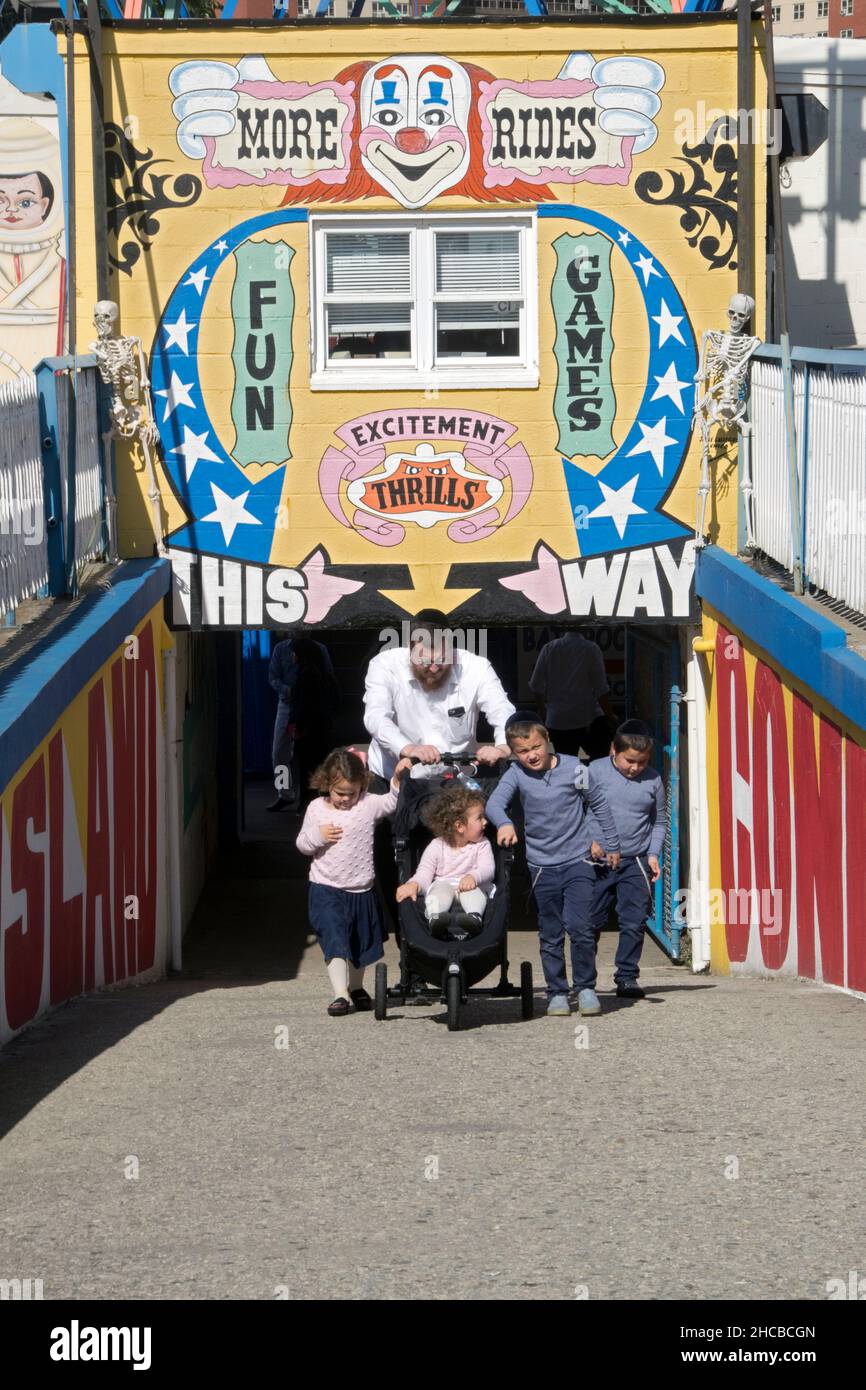 An orthodox Jewish family approaches the Coney Island Boardwalk during the Sukkot holiday where it's mandated to have fun. In Brooklyn, New York Stock Photo