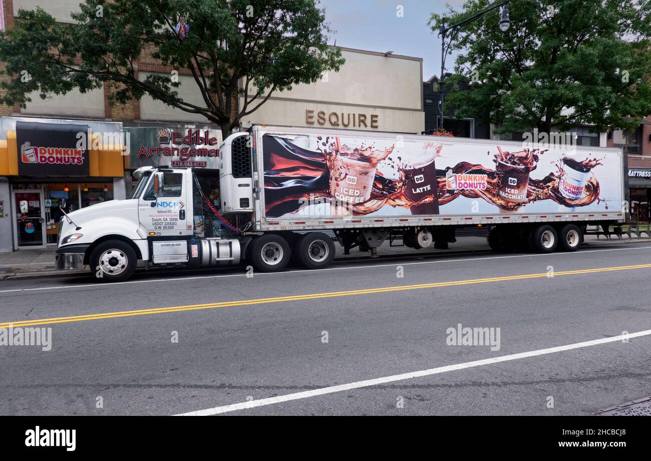 A huge Dunkin' Donuts semi delivery truck delivers to a shop on Steinway Street in Astoria, Queens, New York City. Stock Photo