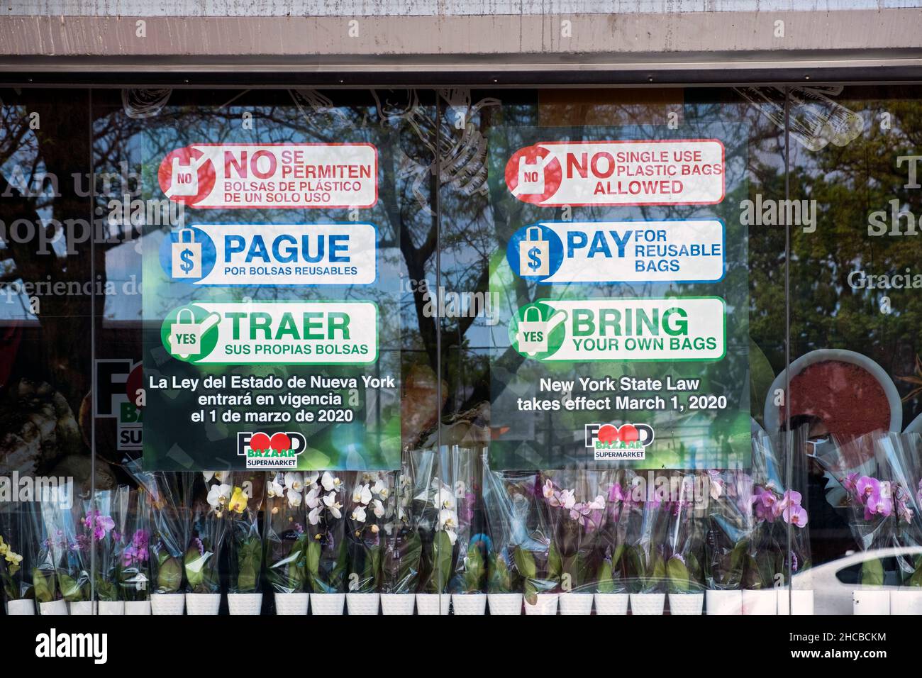 Signs on supermarket window saying that plastic bags were banned, paper bags would cost & urging customers to bring their own. In Corona, Queens NYC Stock Photo