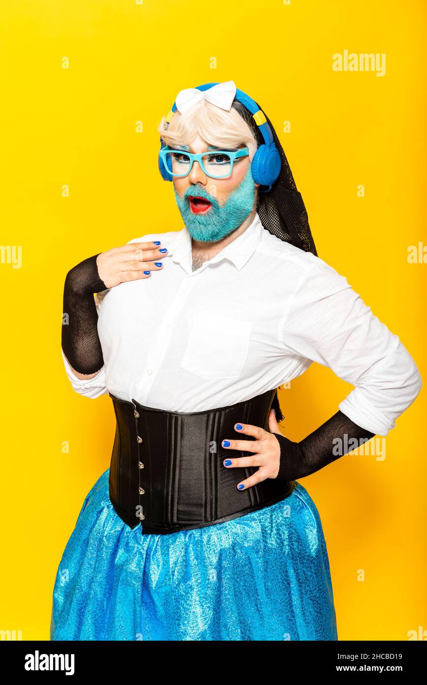 Man with make-up of drag queen dancing and shouting against yellow background Stock Photo