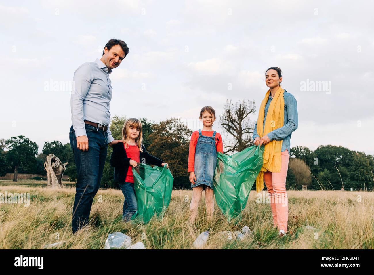 Family with garbage bags doing cleanup in park Stock Photo