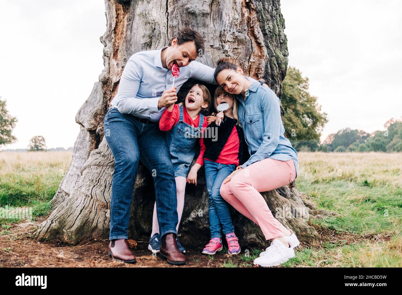 Happy family enjoying lollipops near tree in park Stock Photo