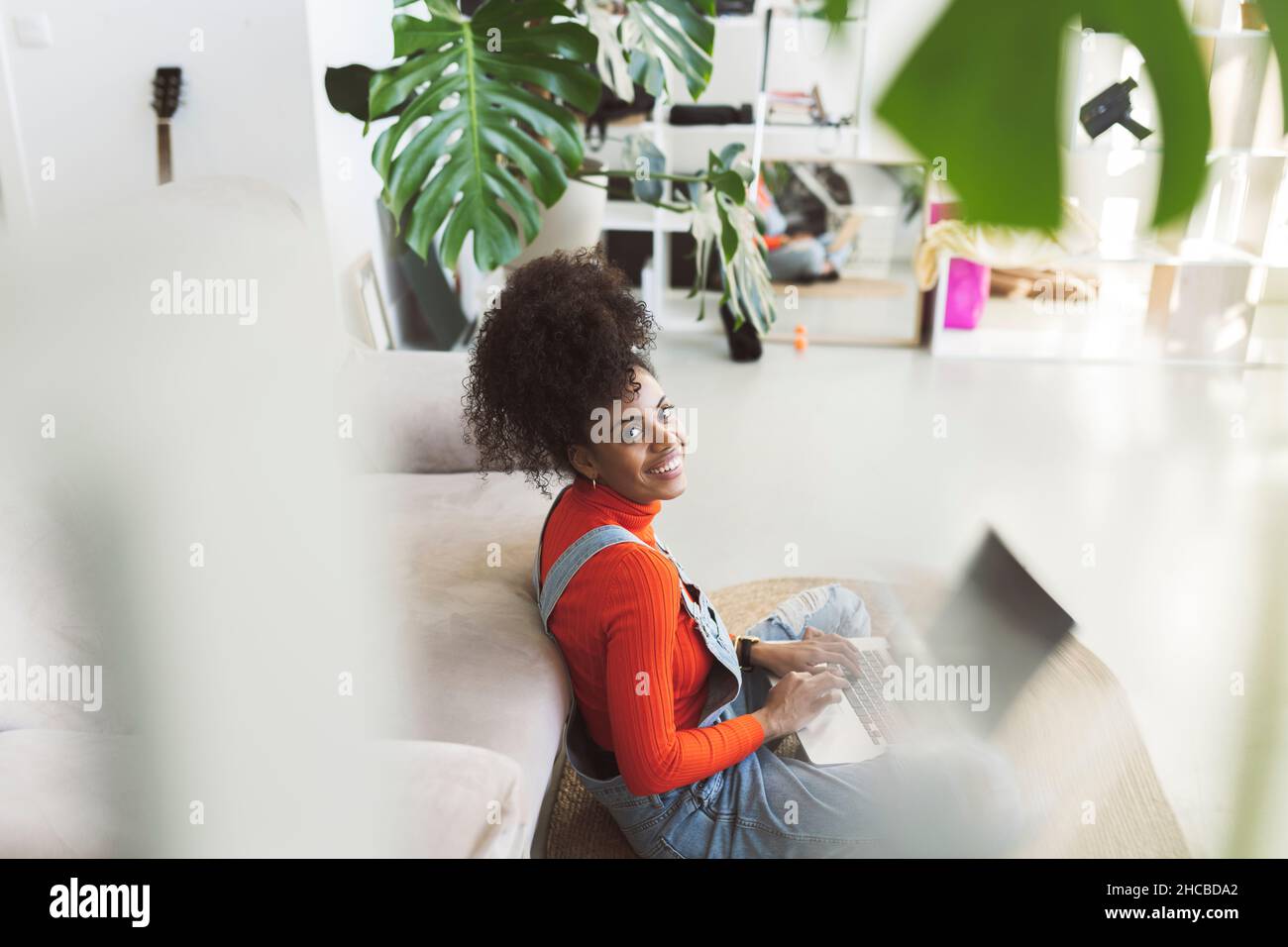 Curly haired woman using laptop at home Stock Photo