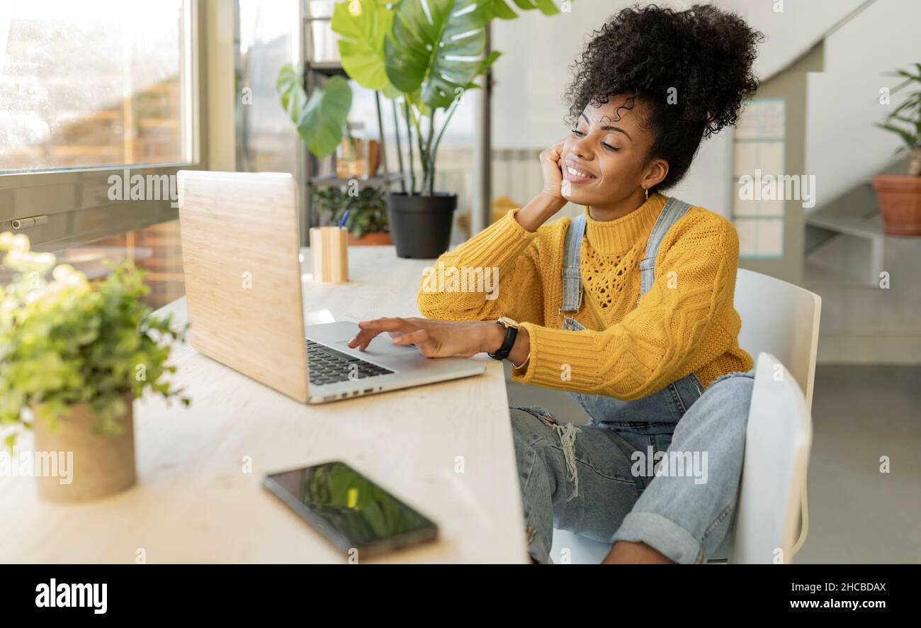 Smiling woman greeting on video call through laptop at table Stock Photo