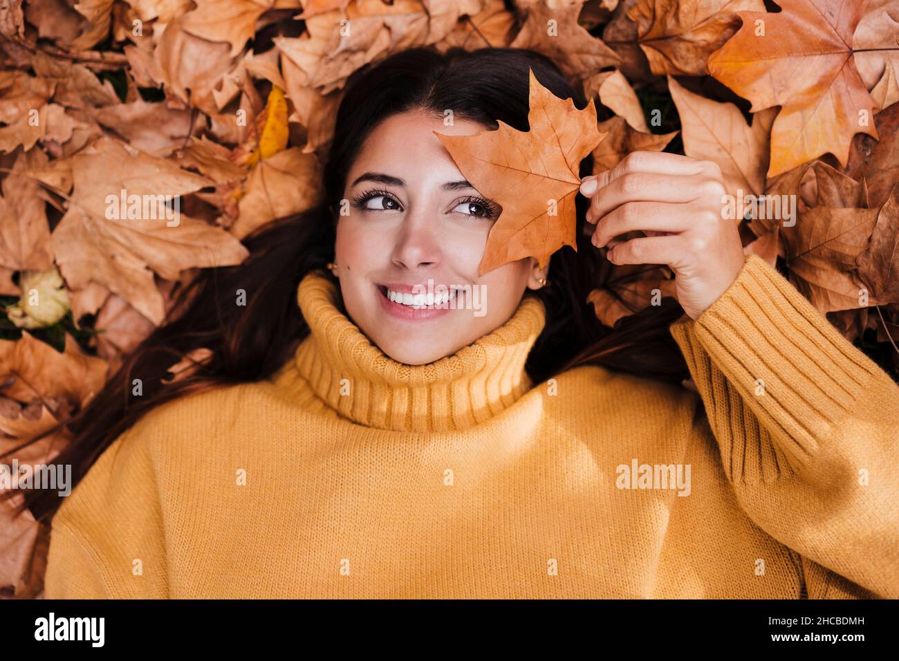 Smiling woman holding dry maple leaf Stock Photo